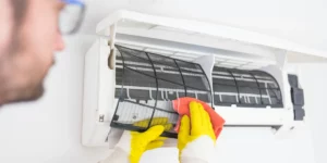 man using a soft brush to clean heat pump filters